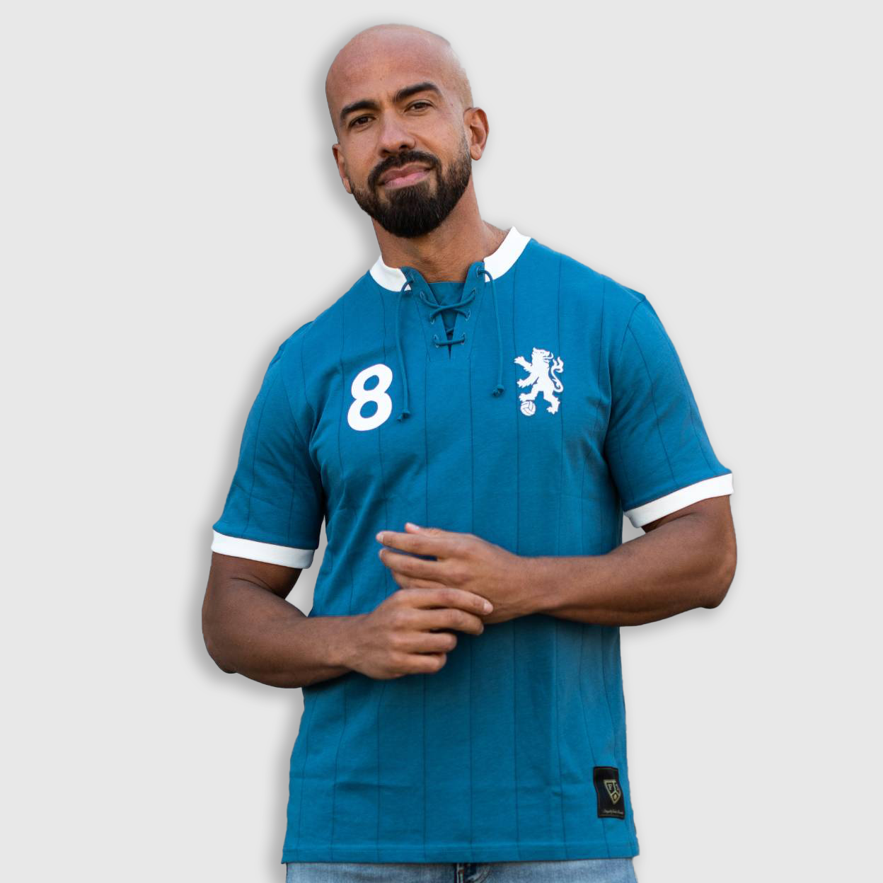 A man wearing a blue retro soccer jersey with white number 8 and a lion emblem on the front.