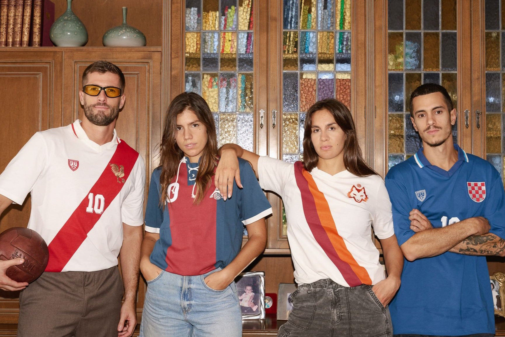 Four people wearing sports jerseys in a room with wooden cabinets and decorative items.